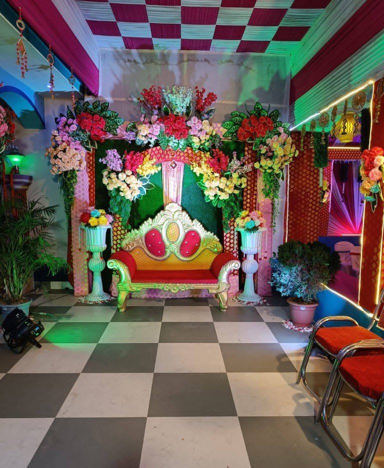 Indoor wedding mandap with floral arch and ornate seating